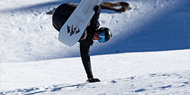 Person doing a handplant on a snowboard